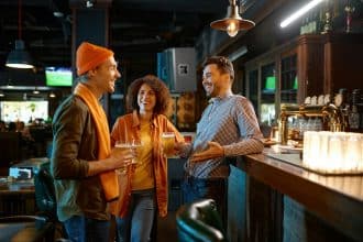 Groupe d'amis discutant joyeusement autour d'un bar avec des boissons